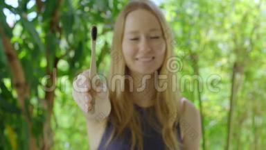 一位年轻女子展示了<strong>一把</strong>竹子做的木制牙刷。环保零废竹产品理念
